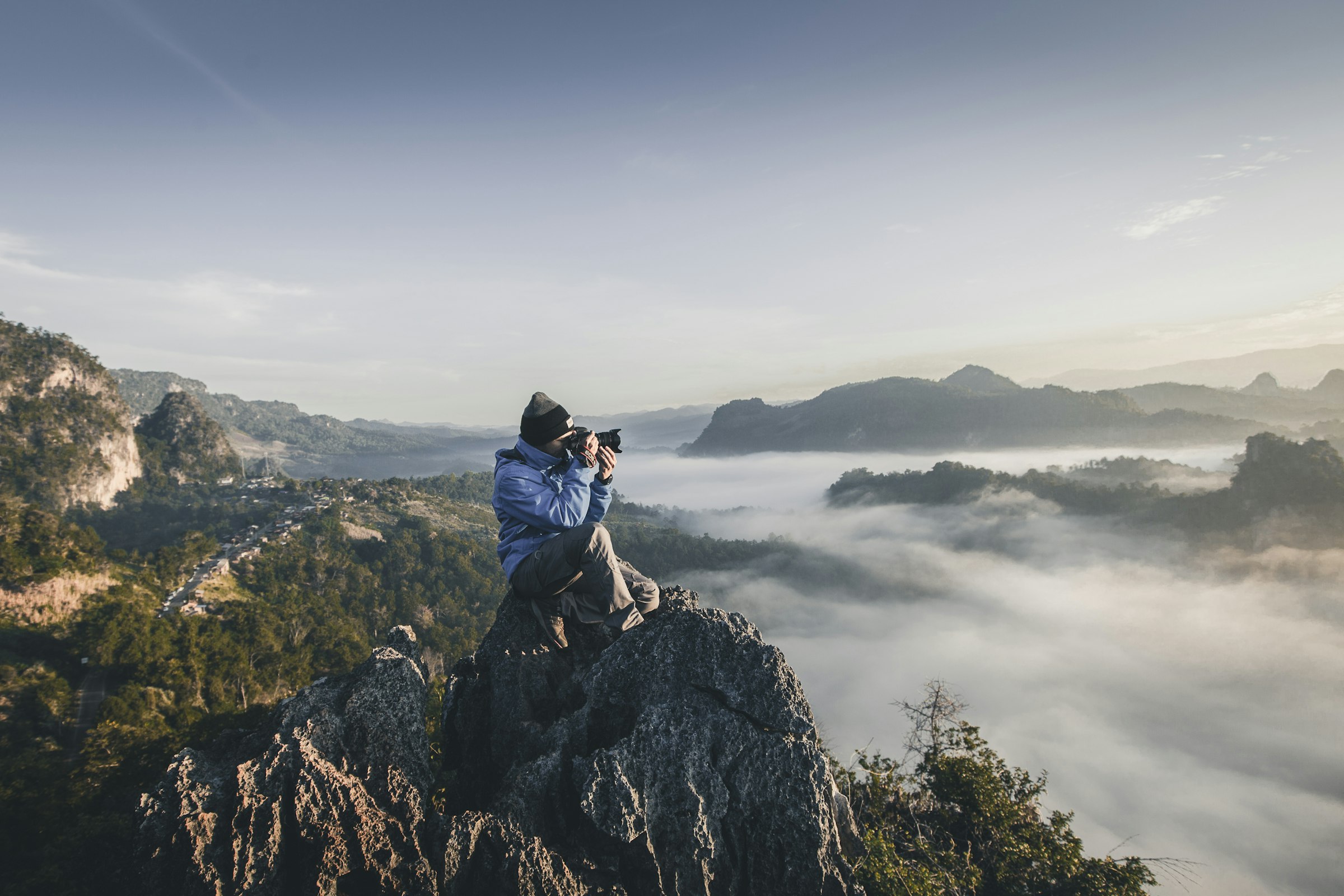A photographer shooting from a ridge above a valley of low cloud