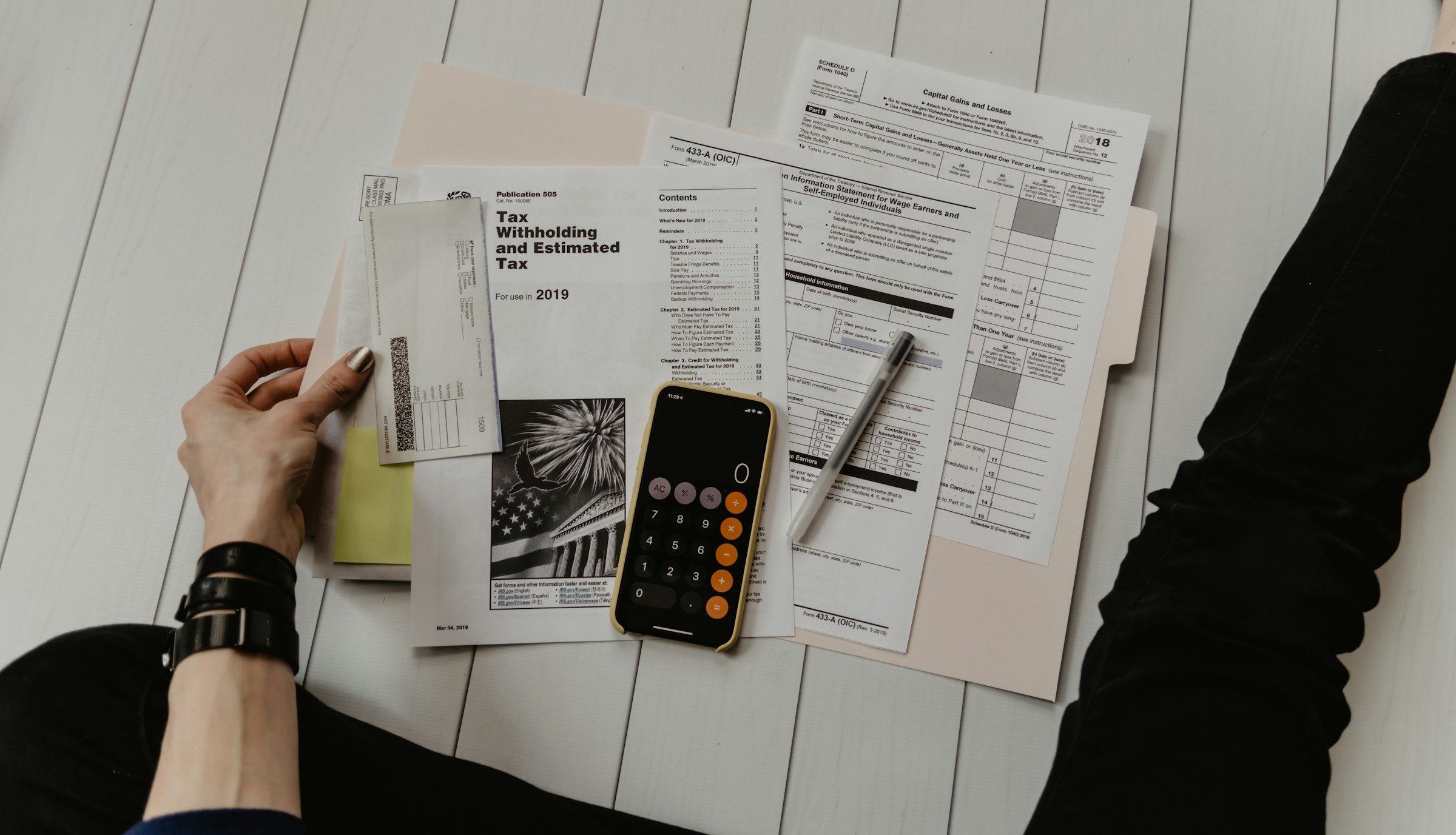 Tax forms, a calculator and a pen spread across a desk